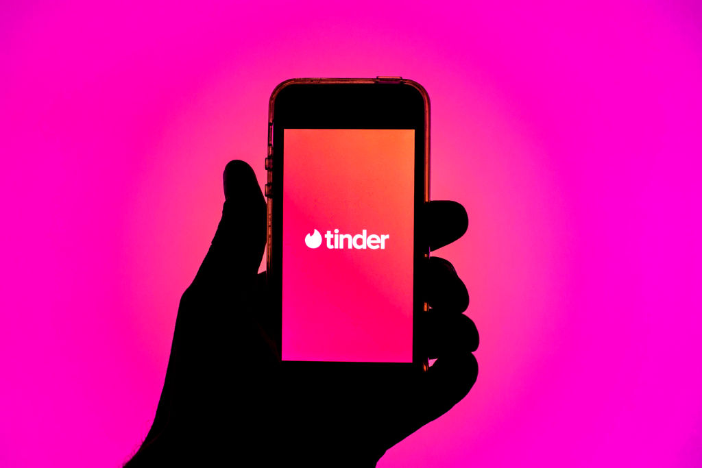 In this photo illustration, the Tinder app seen displayed on...
