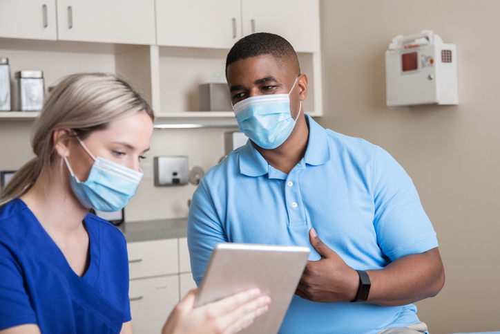 Nurse holds digital tablet while talking to patient