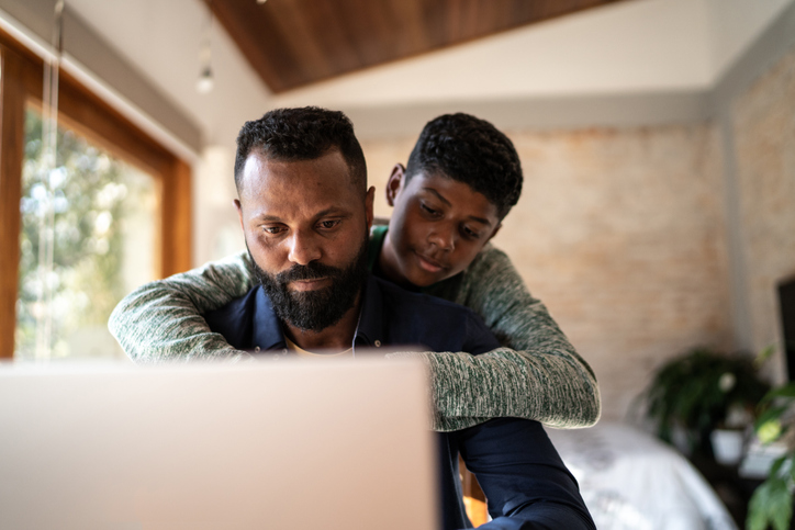 Son embracing father while he's working at home