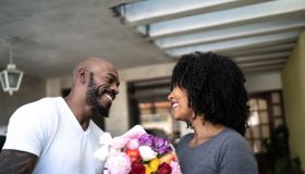 Husband surprising his wife with a flowers and present at home
