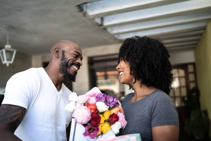 Husband surprising his wife with a flowers and present at home