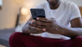 Young man text messaging while sitting on bed at home