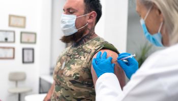 Doctor injecting COVID-19 vaccine to soldier