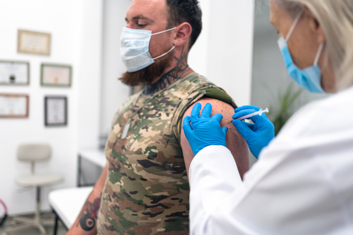 Doctor injecting COVID-19 vaccine to soldier