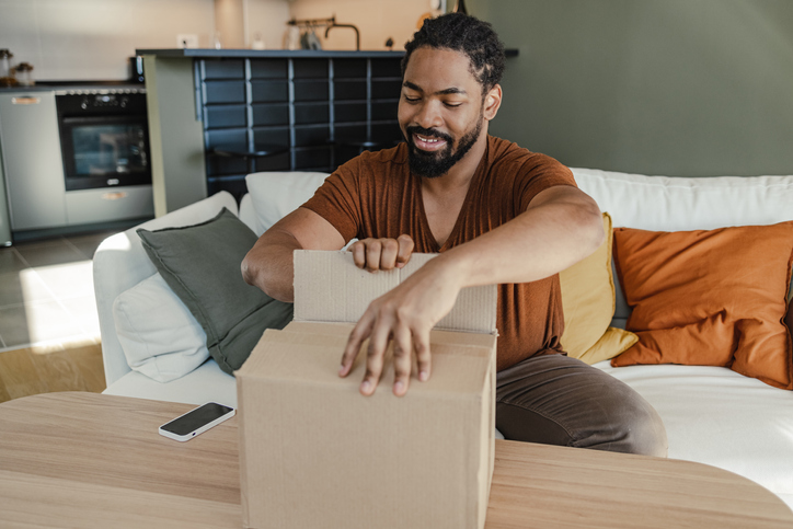 Young man unpacking the box in which his online order has arrived