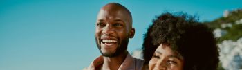 Young happy black couple smiling, bonding and walking on beach together during summer on the weekend. Loving husband and wife embracing, enjoying a romantic getaway and relaxing on honeymoon