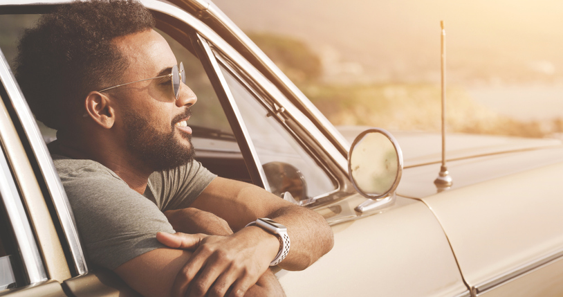 Relaxing, smiling and happy male on a car road trip taking a break to enjoy a beautiful nature view. Relaxed man with a smile embracing travel life. Content guy feeling happiness enjoying his journey