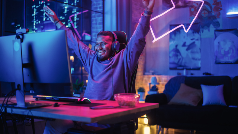 Gaming at Home: Black Gamer Playing Online Video Game on Personal Computer. Stylish African American Male Player Enjoying Online Tournament in His Loft Apartment.