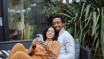Happy young African American couple using smart phone