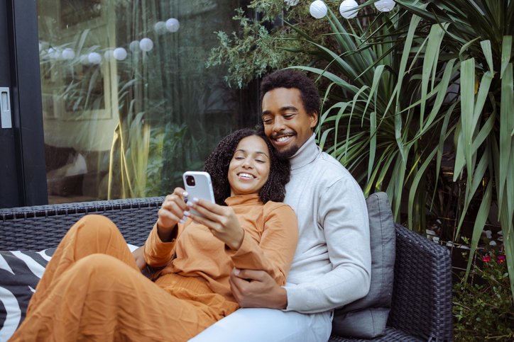 Happy young African American couple using smart phone