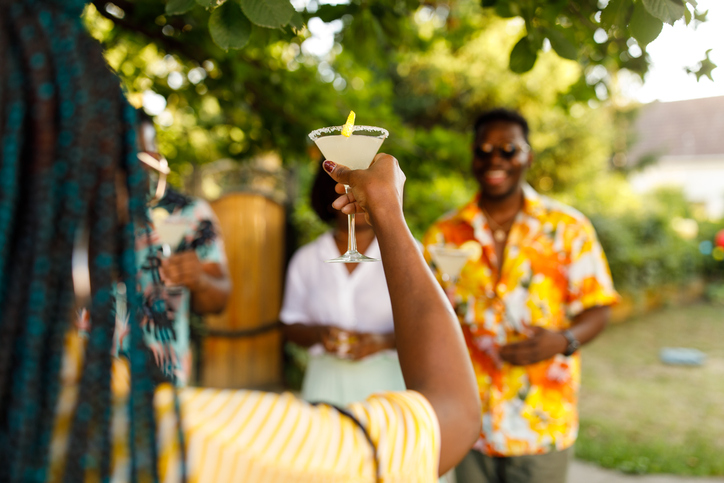 Young woman raising her glass and proposing a toast during a summer garden party with friends