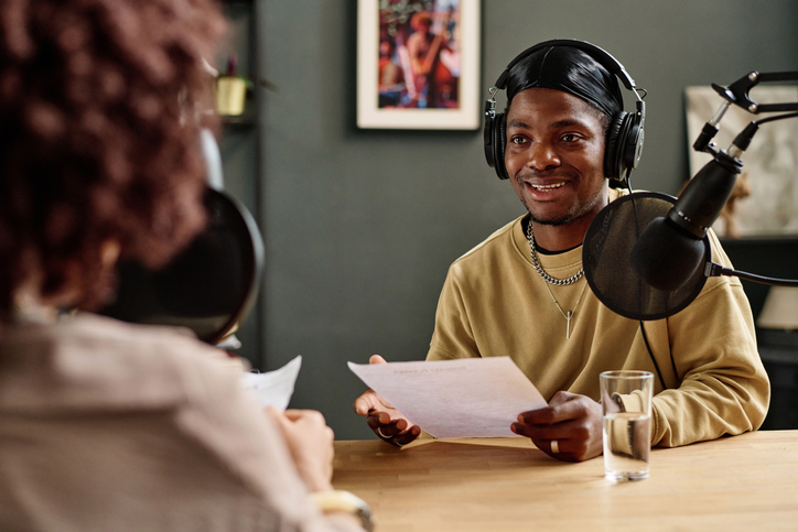 Young African American man with paper speaking in microphone