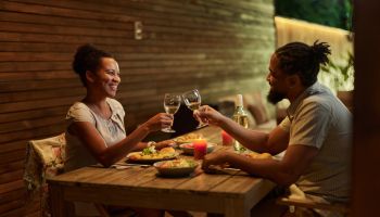 Happy black couple toasting during dinner on a patio.