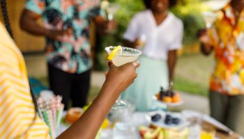 Young woman enjoying a glass of margarita cocktail during a summer garden party