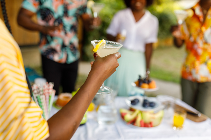 Young woman enjoying a glass of margarita cocktail during a summer garden party