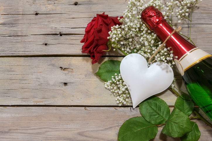 White heart, champagne bottle and a red rose on a rustic wooden table, romantic love concept for Valentine's, Mother’s or Father’s day, copy space, top view from above