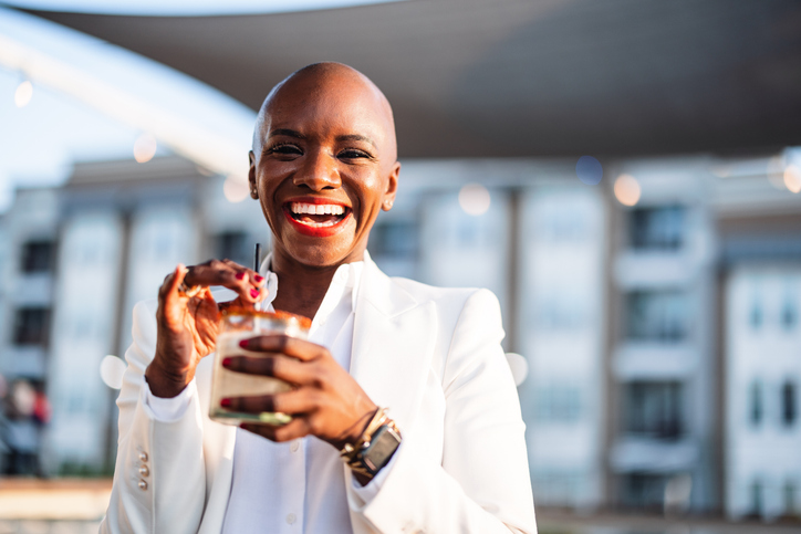 Cheerful Black Woman Enjoys Cocktail on Terrace