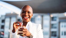Cheerful Black Woman Enjoys Cocktail on Terrace
