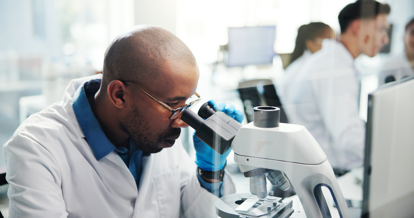 Microscope, scientist and man with exam for research in laboratory, healthcare and medical innovation. Science, experiment and microbiology for drugs development, pharma study and biotechnology test