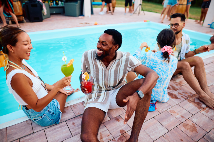 Friends enjoying cocktails by the pool during a summer party