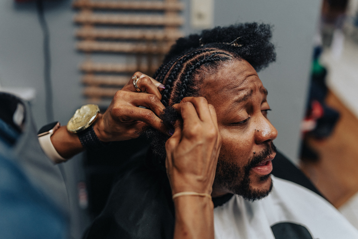Man having hair braided in barber shop