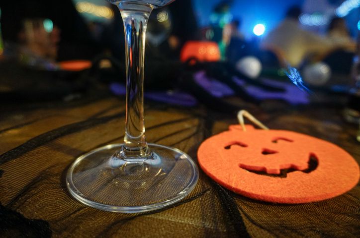 A glass of white wine and a handmade felt pumpkin on a table at the Halloween party