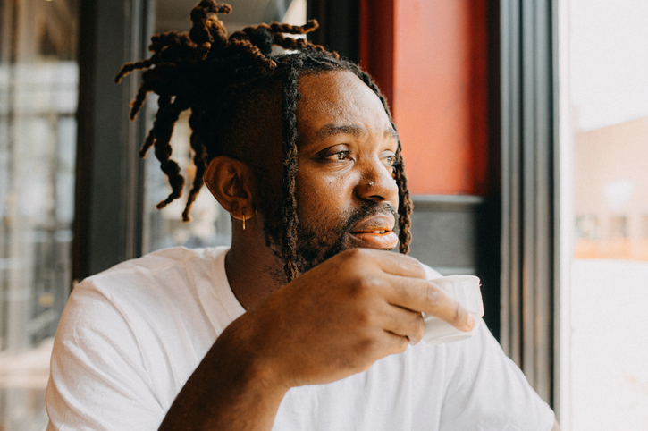A man gazes thoughtfully while holding an espresso cup