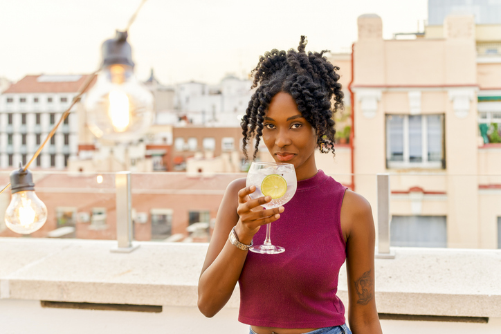 Young woman enjoying a gin and tonic on a rooftop bar