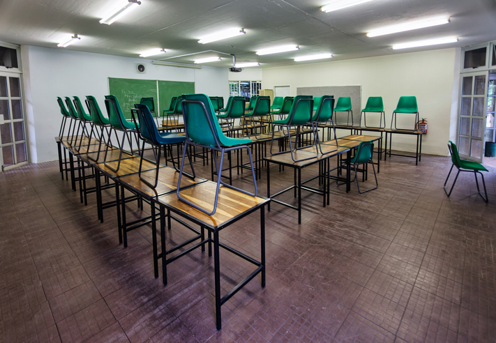 Empty Classroom with Green Chairs Stacked on Wooden Desks Ready for Students