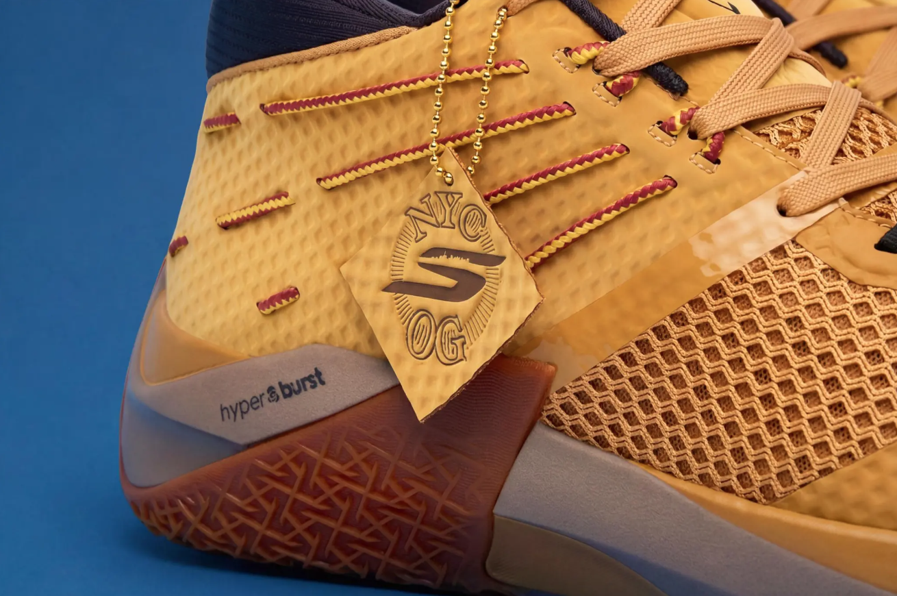 Close-up of a yellow athletic shoe with a "Snyg" logo and "hyperburst" text, against a blue background.