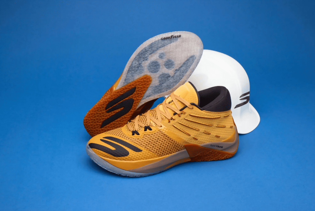 A pair of yellow and black athletic shoes with a white sole on a blue background.