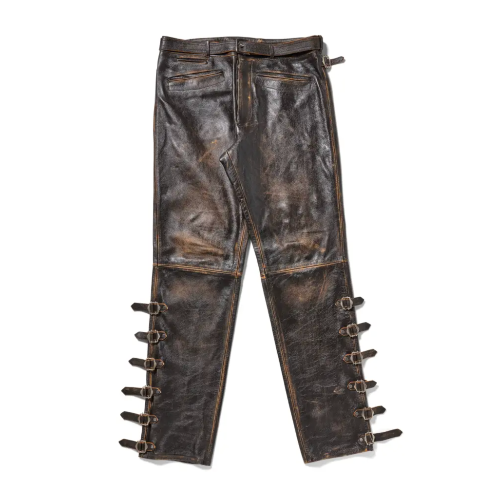 Worn leather pants with multiple buckle straps and distressed detailing.