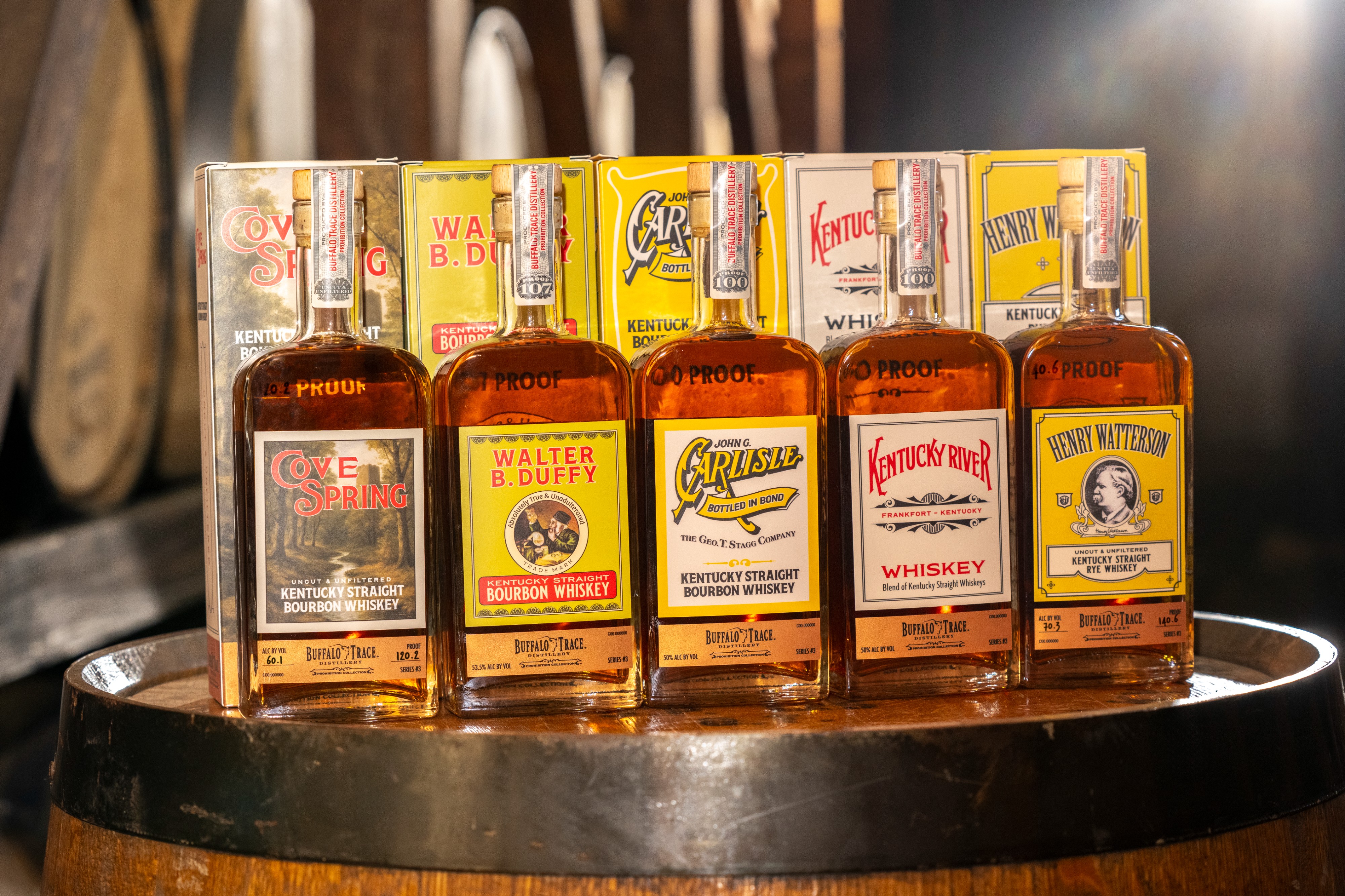 Assortment of Kentucky bourbon whiskey bottles, including brands like Evan Williams, Walter B. Duffy, and Henry Watterson, displayed on a wooden barrel.