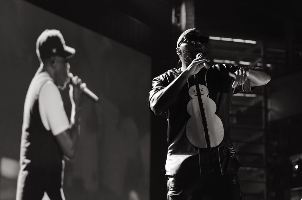 Two musicians performing on stage, one playing a cello and the other singing into a microphone.