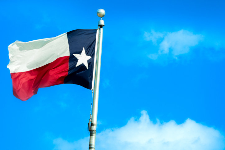 Texas state flag waving against bright blue summer sky in Bryan Texas USA