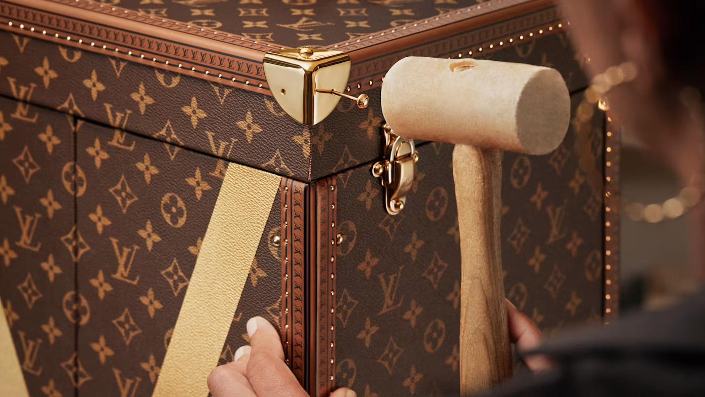 A close-up view of a Louis Vuitton monogram trunk, showing the intricate pattern and metal hardware.