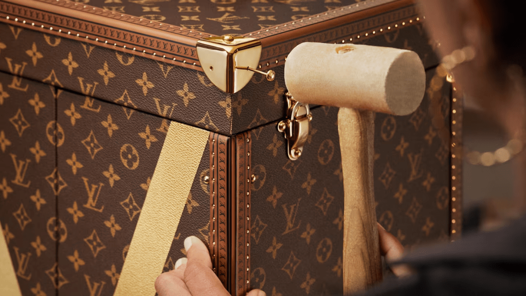 A close-up view of a Louis Vuitton monogram trunk, showing the intricate pattern and metal hardware.