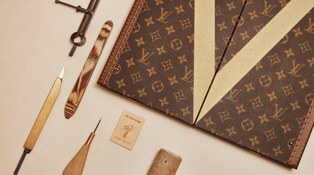 A Louis Vuitton monogram pattern book with various leather tools and accessories arranged on a beige background.