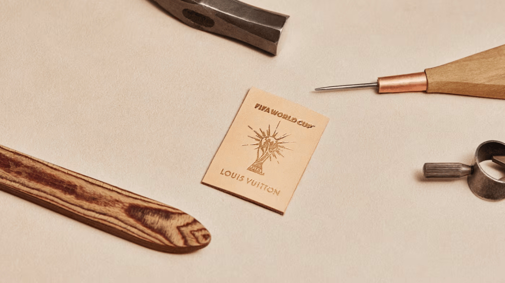 A wooden tool, a Louis Vuitton logo, and other workshop items on a beige surface.