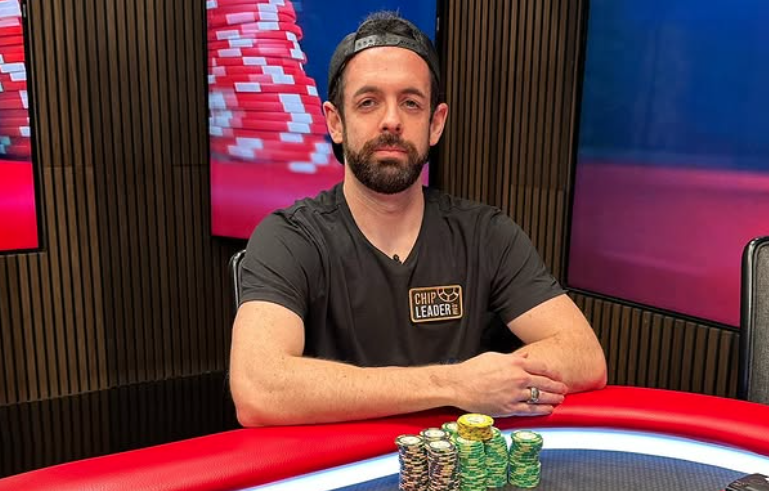 A man with a beard wearing a "Chip Leaders" t-shirt sitting at a poker table with poker chips in front of him.