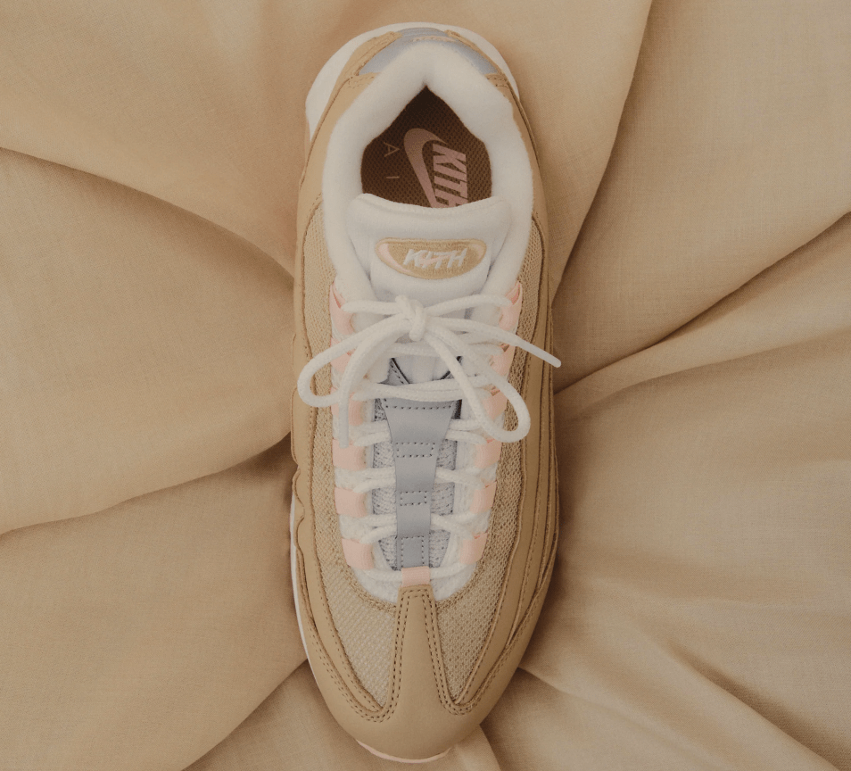 A close-up view of a beige Nike Air Max 95 sneaker with white laces and the Nike logo visible on the side.