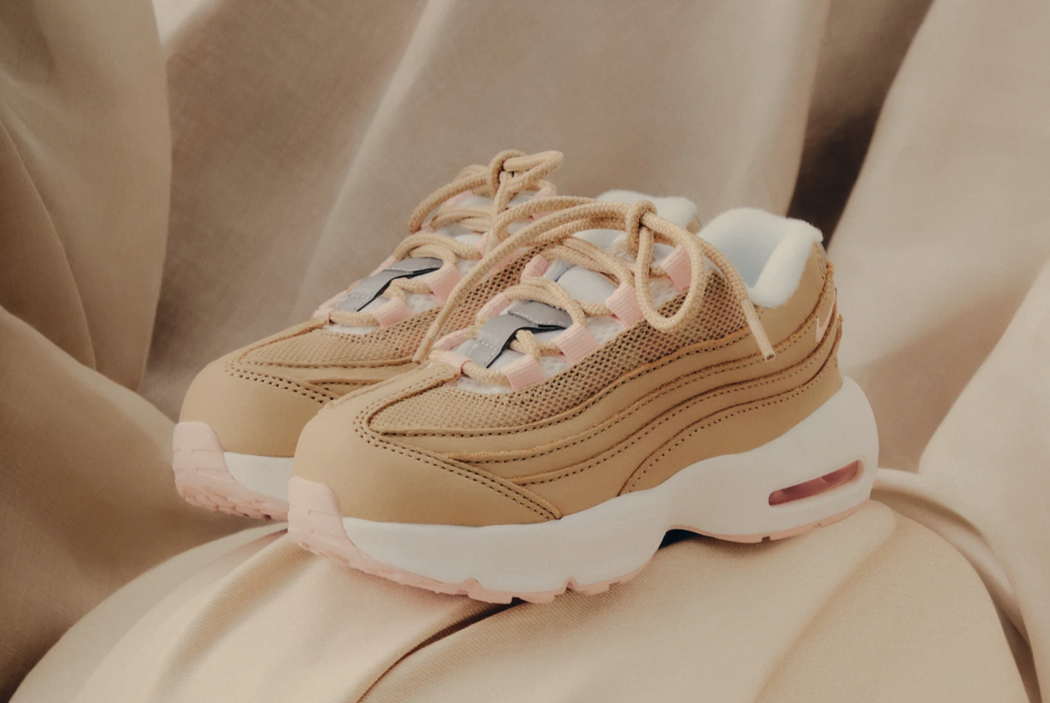 Pair of beige and white athletic shoes with laces on a beige background.