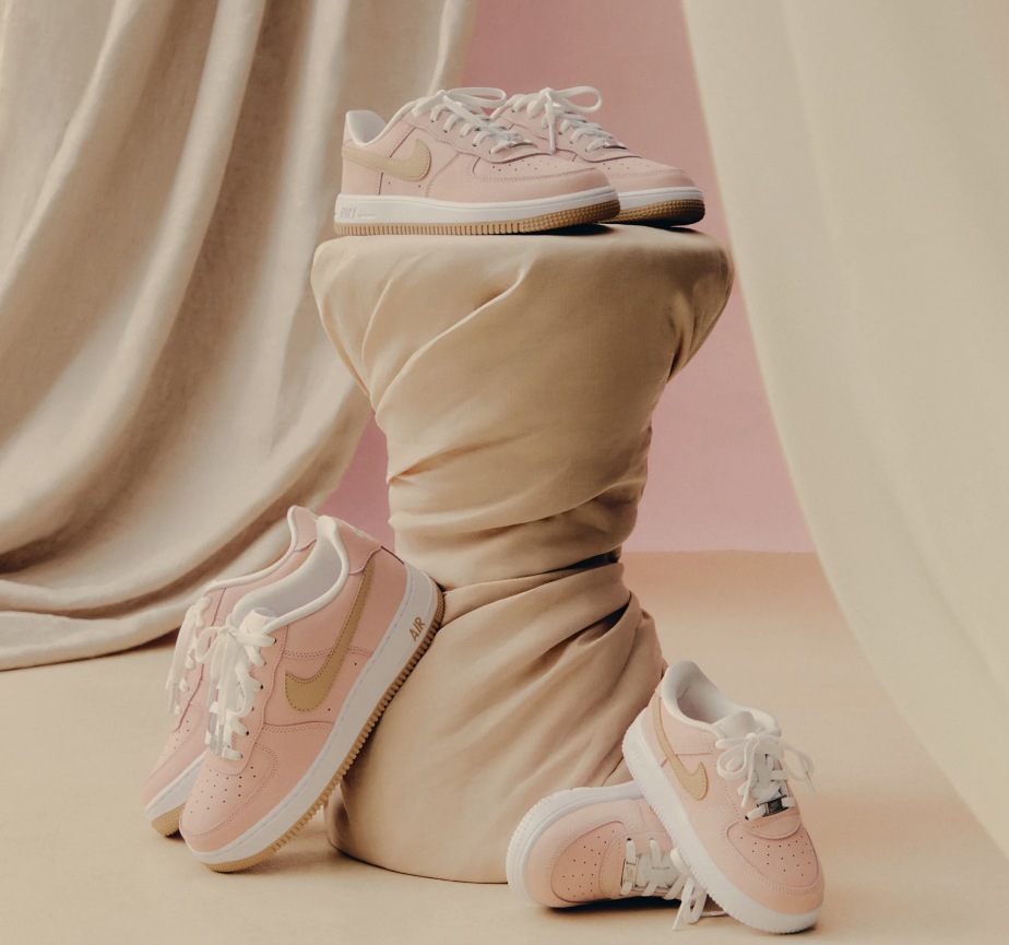A pair of pink Nike Air Force 1 sneakers on a beige cloth, with the shoes partially wrapped in the fabric.