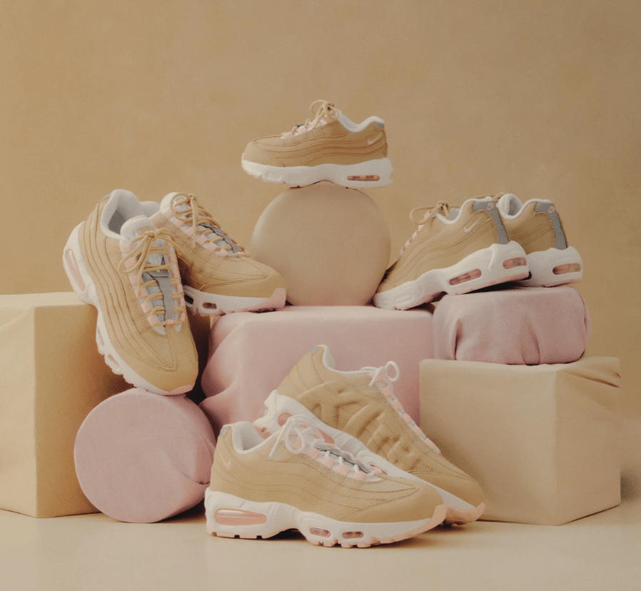 Assortment of beige and pink Nike Air Max 95 sneakers and accessories arranged on a neutral background.