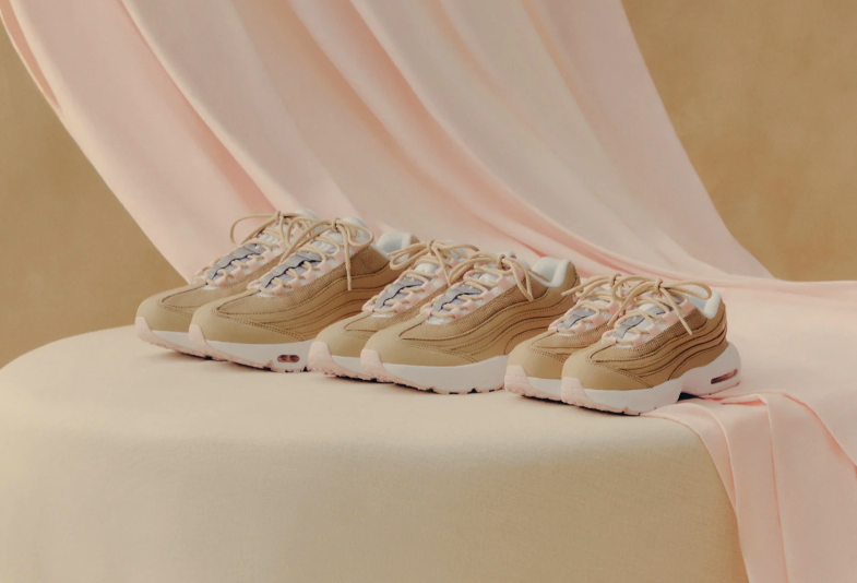 A row of beige and white sneakers with floral accents on a pink fabric backdrop.