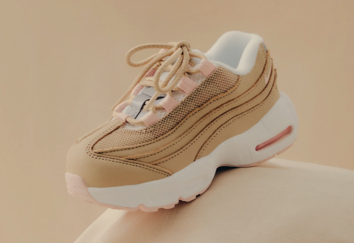 Beige athletic sneaker with white sole and laces, featuring a mesh upper and air cushion design.