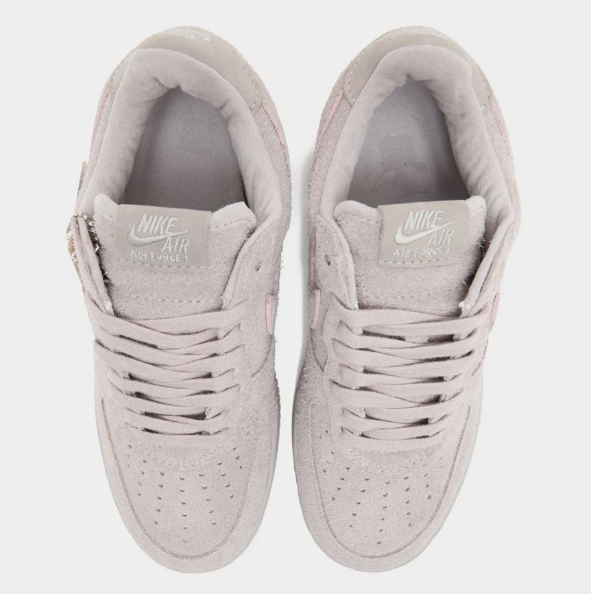 A pair of light gray Nike Air Force 1 sneakers with the Nike logo visible.