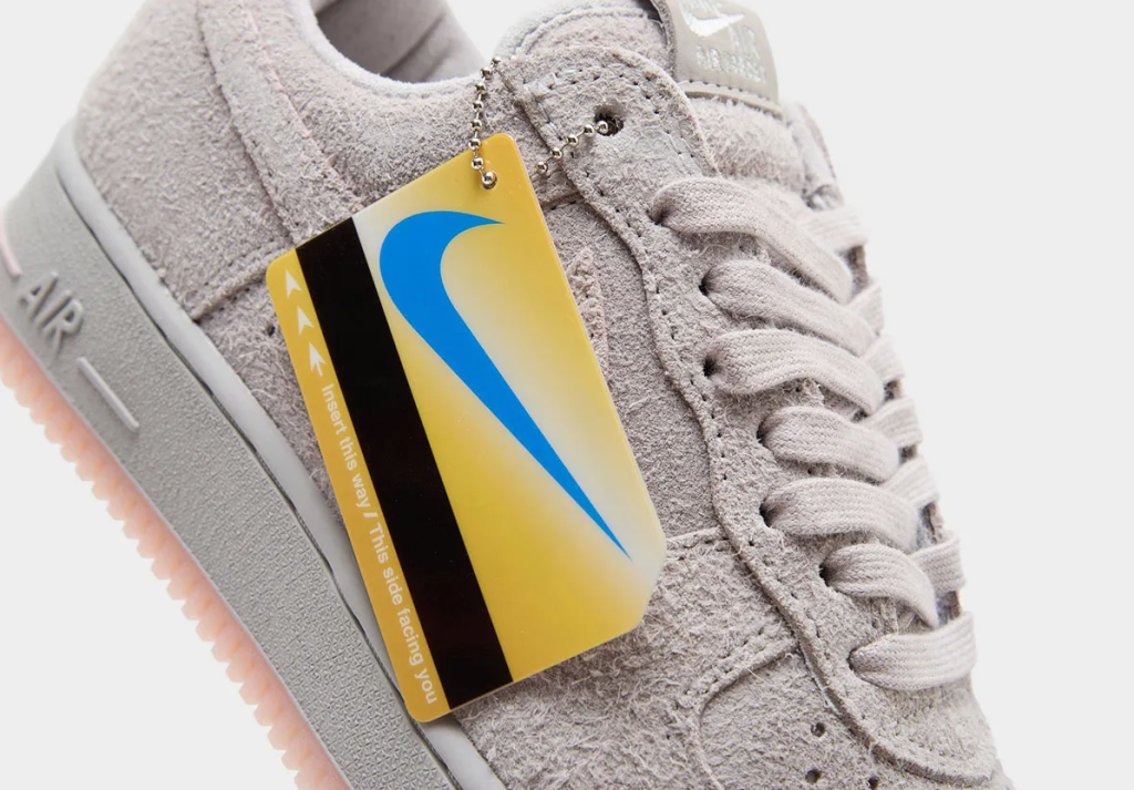 Gray sneaker with Nike swoosh logo and yellow and blue tag attached.