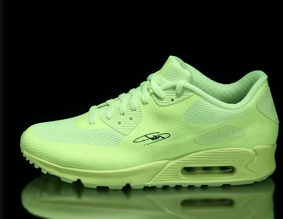 Bright neon green Nike Air Max 90 sneakers with visible Air Max branding on a black background.