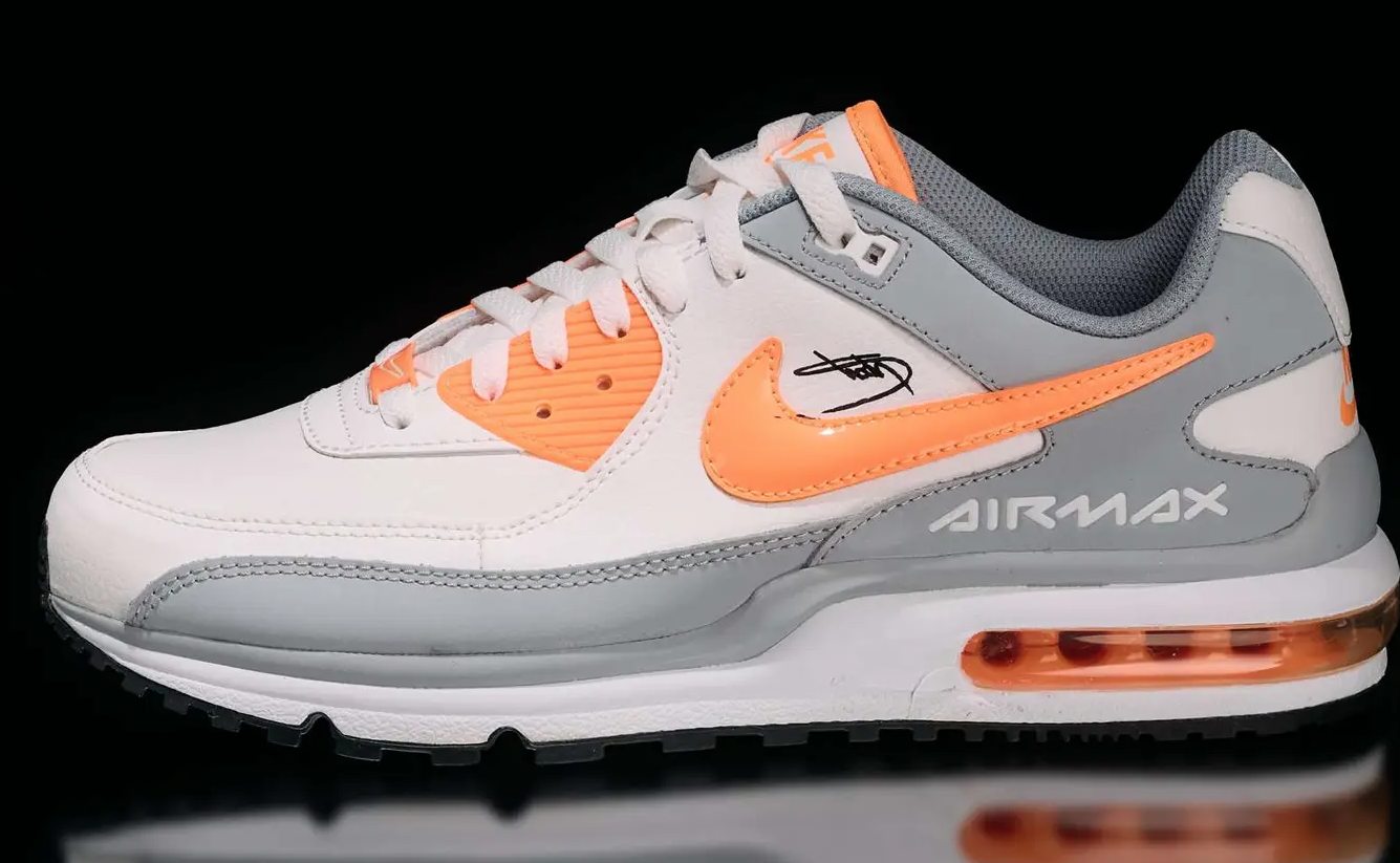 A pair of white and orange Nike Air Max sneakers with gray accents and the Air Max branding visible.